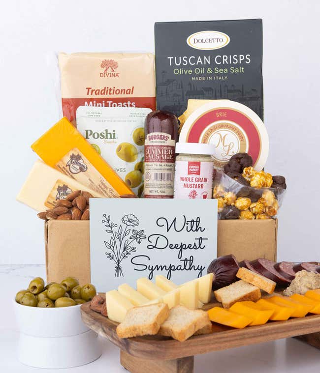 A gourmet charcuterie gift set featuring Tuscan crisps, focaccia crackers, smoked cheddar, brie spread, olives, mustard, sausage, almonds, chocolate-covered popcorn, and finished with a Sympathy card to show your support.